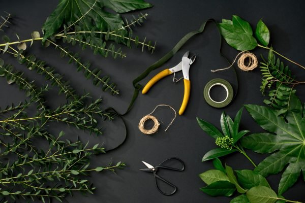 Tools and accessories florists need for making up a bouquet. The black florist workplace. Top view. eucalyptus leaves